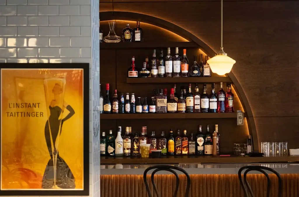 Jean Claude’s curved wooden bar, French poster and warm lighting